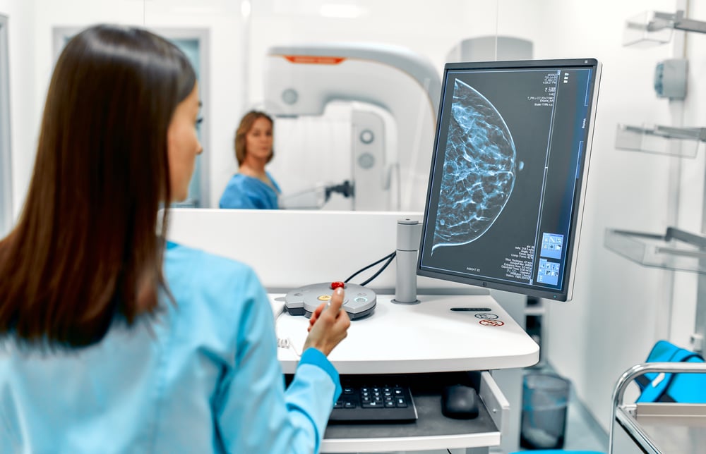 Technologist reviewing a mammogram image on a workstation during a breast imaging exam